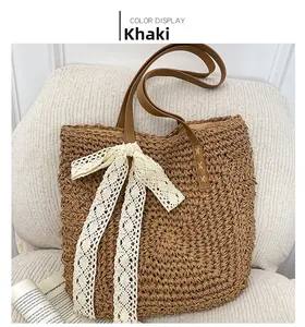 Detail of khaki straw tote bag featuring a white lace bow and brown leather handles