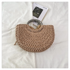 Detail view of semi-circular straw bag with black and white striped ring handles