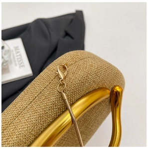 Macro detail of acrylic woven handbag featuring golden hardware and wavy metallic handle