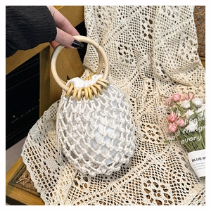Detail of white cotton rope beach bag with wooden ring handles and drawstring liner