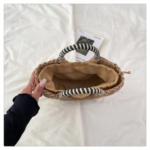 Detailed view of handmade woven straw bag with striped handles and drawstring lining