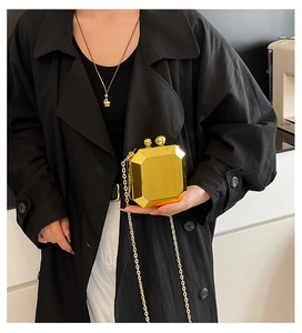 Detail of a geometric octagon evening clutch with gold polished finish and metal chain