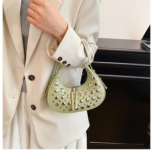 Close-up of pale green crescent bag with silver stud rivets worn with a cream suit