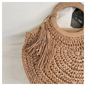 Detail of round straw bag showing intricate weave texture and elegant tassel accent