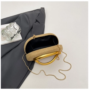 Detail of woven straw clutch with gold circular handles and interior compartment