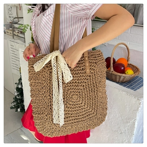 Detailed macro view of woven raffia texture and delicate cream lace bow on tote bag