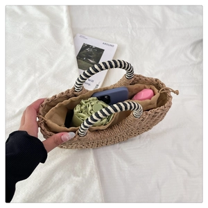 Detail of straw handbag with striped handle, drawstring lining and daily essentials storage