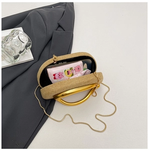 Macro detail of straw woven clutch with gold metal handle and interior compartment