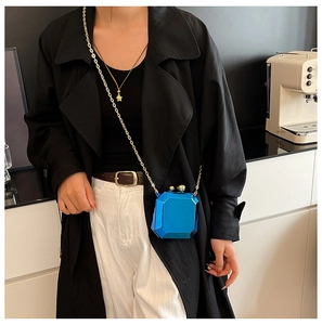 Detail view of a blue geometric acrylic clutch bag with a gold clasp and chain strap