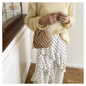 Detail of woven beach tote featuring wooden handle and drawstring inner pouch bag