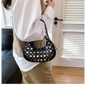 Detail of black crescent hobo bag with silver studs and double zipper on shoulder