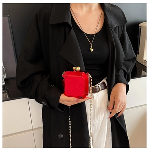 Detail of red geometric acrylic clutch bag with gold chain and ball clasp on model