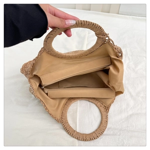 Detail view showing internal fabric lining and zipper pocket of the woven straw beach bag