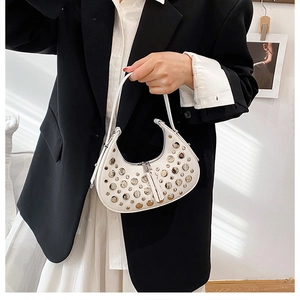 Close-up of white crescent bag with silver rivet studs and smooth leather handle