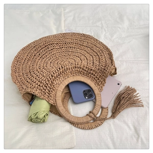 Detail of round straw bag showing spacious interior with tassel and woven texture