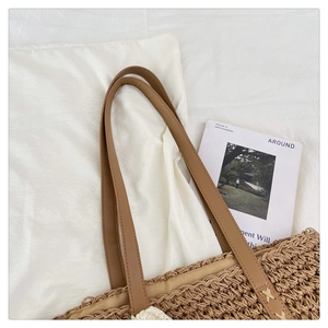 Detail of raffia woven tote with premium brown leather straps and cross-stitching