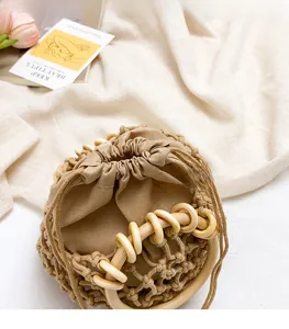 Top view of woven drawstring bag with round wooden handles and cotton inner pouch