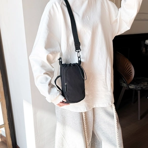 Detail of multi-functional black canvas crossbody bag with adjustable strap and front pocket