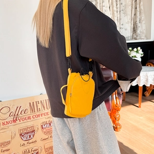 Detail view of a bright yellow nylon crossbody bag with drawstring closure on a model