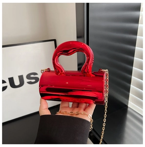 Detail of red cylindrical mini evening bag with glossy mirror finish and gold chain