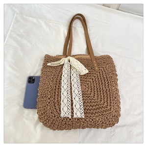Brown straw tote bag with lace bow detail and leather handles showing size reference