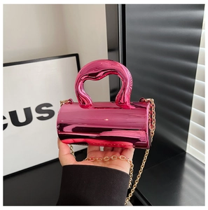 Close-up of bright pink metallic cylinder handbag with gold chain strap and mirror finish