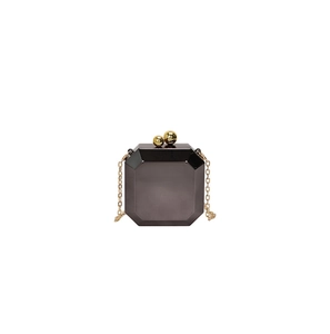 Detail view of hexagonal acrylic clutch bag with gold spherical clasp and chain strap