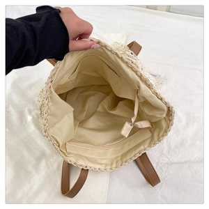 Detail view of raffia tote bag showing inner lining with zipper pocket and lace trim