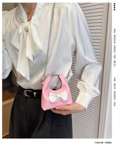 Close-up of pink mini crossbody bag with white bow detail and silver metal chain strap