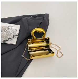 Close-up of gold hard shell evening bag with heart handle and polished metal finish