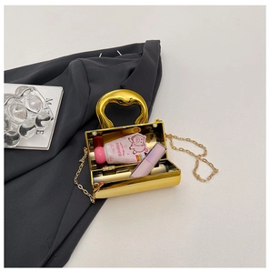 Detailed top view of gold mini evening bag with metal handle and chain on dark grey fabric