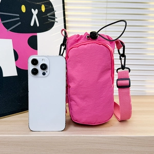 Detail of rose pink nylon crossbody bag with drawstring closure showing smartphone storage space