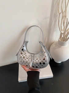 Silver crescent hobo bag with metallic rivets and y2k aesthetic shown in minimalist studio