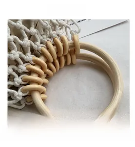 Detail view of woven cotton net bag with natural wooden ring handles for beach