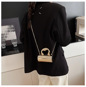 Detailed view of mini gold chain evening bag with heart handle worn cross-body