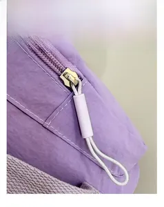 Macro detail of high-quality smooth metal zipper and purple fabric on nylon shoulder bag