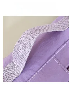 Detail of durable purple woven handle with reinforced stitching on a nylon crossbody bag