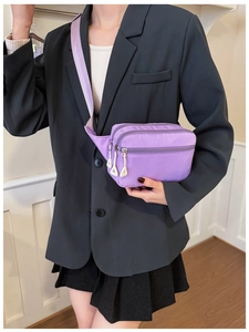 Detailansicht der lila Nylontasche mit drei Reißverschlussfächern und weißen Laschen
