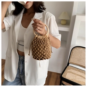 Detail of hand-woven cotton rope bucket bag with round wooden handles and drawstring pouch