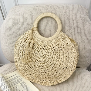 Handmade cream woven straw bag with circular handles and tassel accent for beach vacations