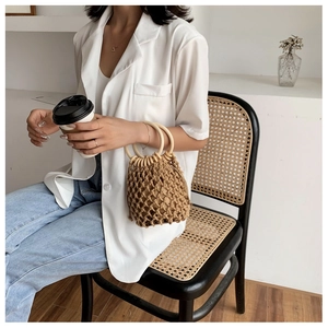 Detail of hand-woven cotton rope bucket bag with round wooden handles and drawstring liner