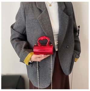 Detail of red cylindrical mini bag with glossy mirror finish and gold chain strap