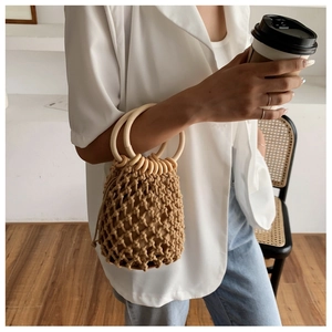 Detail of woven bucket bag with round wooden handle and drawstring liner in casual setting