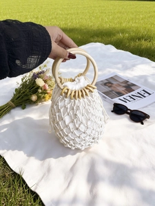 Bohemian white cotton rope woven beach bag with round wooden handles on grass