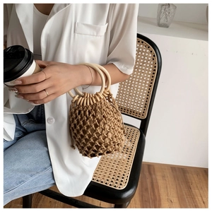 Detail of hand-woven mesh bucket bag featuring round wooden handles and drawstring pouch