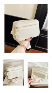 Detailansicht der cremefarbenen Nylon-Gürteltasche mit drei Reißverschlussfächern und Gurt