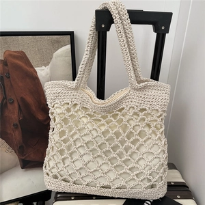 Beige handwoven cotton rope tote bag with mesh pattern on a black suitcase handle
