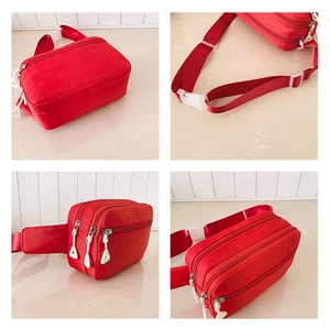 Detailansicht der roten Sport-Bauchtasche aus Nylon mit drei Fächern und weißen Schnallen