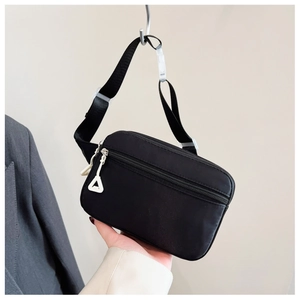 Detail der schwarzen Nylon-Kinderbauchtasche mit mehreren Reißverschlüssen und weißen Zügen
