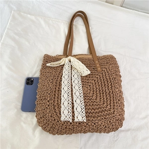 Brown raffia woven tote bag with white lace bow and leather straps for summer beach